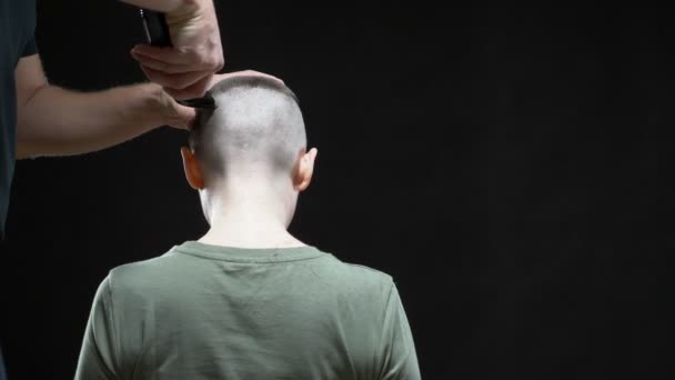 Conceito menina militar. mãos de um homem cabeleireiro barbear uma cabeça de mulher careca, penteado de exército. Fundo preto — Vídeo de Stock