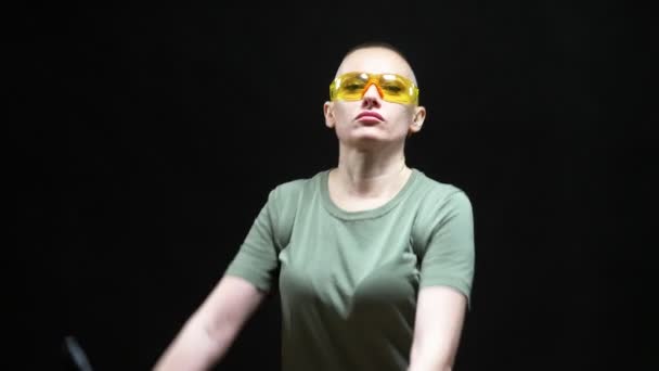 Beautiful bald woman in protective glasses with a heavy bolt cutter in her hands on a black background — Stockvideo