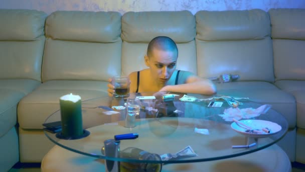 Beautiful sexy bald woman intoxicated drinks alcohol in the living room on the couch. The concept of nightlife and illegal drug use. — Stock Video