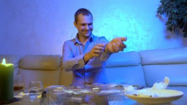 Genç işadamı oturma odasındaki kanepede alkol ve uyuşturucu dolu bir masada otururken kendine uyuşturucu enjekte ediyor.