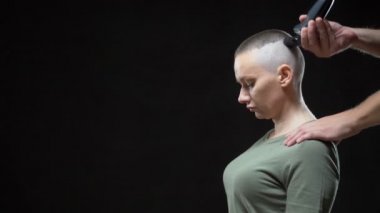 konsept askeri kız. Bir erkek kuaförün elleri bir kadının kafasını tıraş eder, asker saç stili. Siyah arkaplan