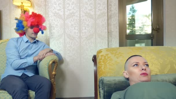 Clownpsykoterapeuten får en skallig kvinnlig klient. Humoristiskt koncept, parodi. Äventyr av främmande människor — Stockvideo