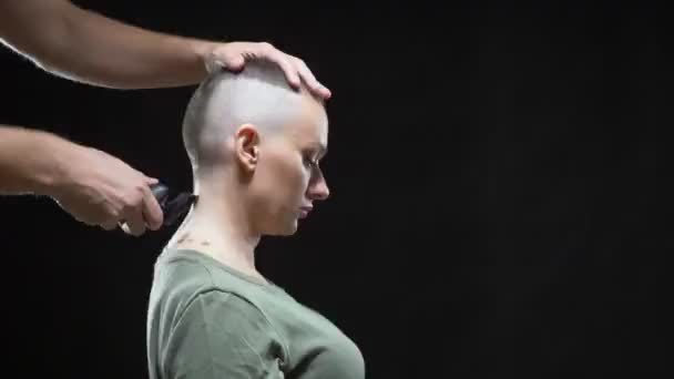 Concept military girl. hands of a man hairdresser shave a womans head bald, army hairstyle. Black background — Stock Video