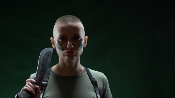 Wütendes glatzköpfiges Mädchen mit Camouflage-Make-up, das Machetenhaare auf schwarzem Hintergrund rasiert — Stockvideo
