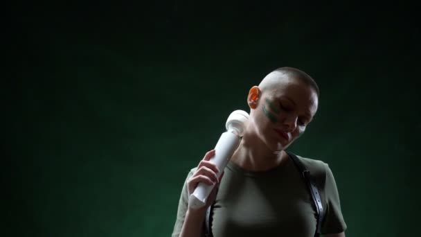 Brutal mujer calva con maquillaje de camuflaje sostiene un masajeador blanco en su mano — Vídeos de Stock