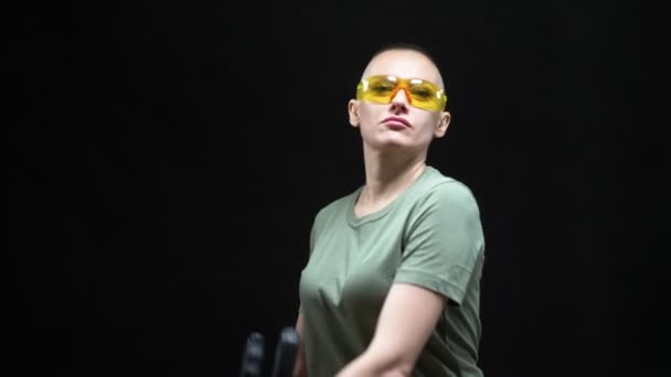 Beautiful bald woman in protective glasses with a heavy bolt cutter in her hands on a black background — Stock Video