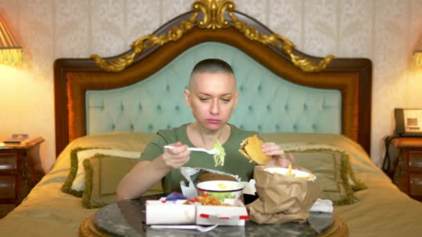 Oholená plešatá žena jíst rychlé občerstvení v hotelu — Stock video