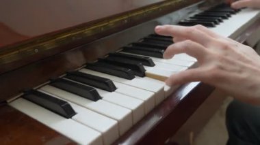 Yakın plan. Kadın elleri usta bir şekilde piyanoda arpeggio çalar.