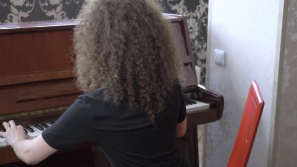 Menina bonita em óculos com cabelo encaracolado toca piano. vista lateral — Vídeo de Stock