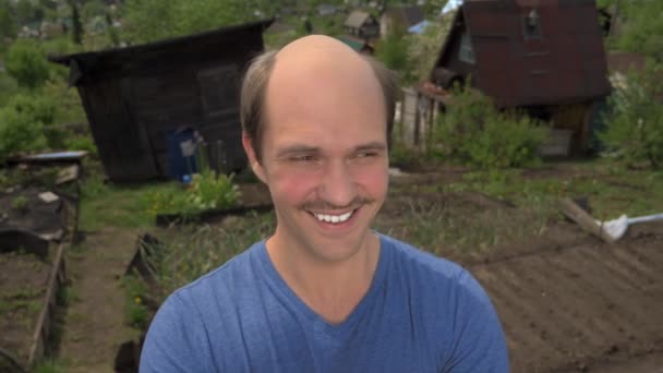 Portré, kopaszodó fiatal férfi vidéken nézi a kamerát, mosolyog — Stock videók