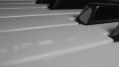 Piyano klavyesinin siyah beyaz tuşlarına yakın çekim. Boşluğu kopyala