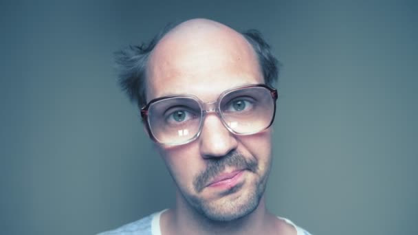 Primer plano. hombre calvo bigotudo en gafas mira y sonríe — Vídeo de stock