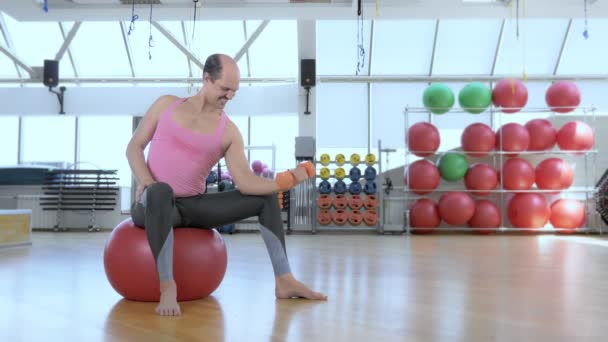 Full height. Bald funny man is training with dumbbells in the gym. — Stock Video