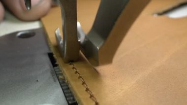 Süper yakın plan. Ayrıntılı dikiş makinesi deri bir ürüne dikiş atar