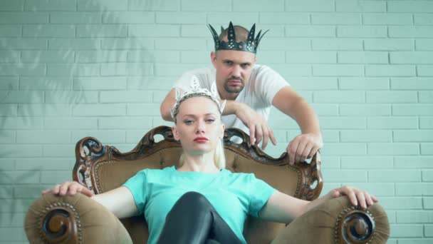 Modefulla moderna par man och kvinna i kronor sitter på tronen — Stockvideo