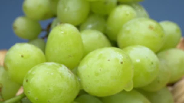 Super de perto. Detalhes de uvas verdes em uma cesta em um fundo azul — Vídeo de Stock