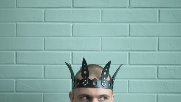 閉鎖だ。レンガの壁の背景に黒い革の王冠の男の頭 — ストック動画