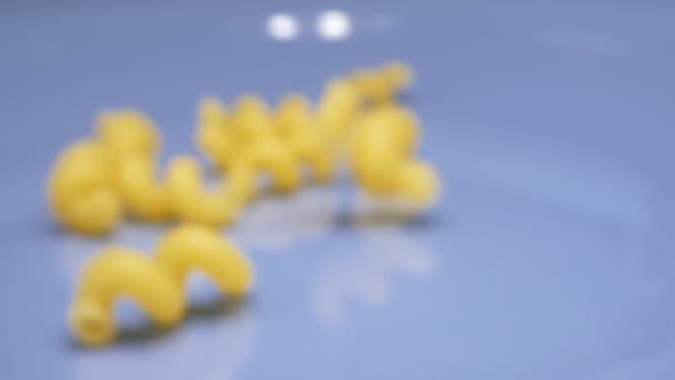 Droge macaroni spiralen bestrooien in een blauwe plaat. superclose-up — Stockvideo