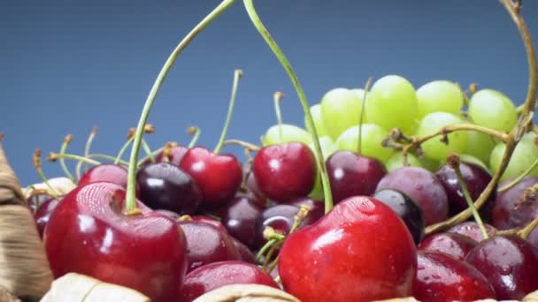 Veldig nærme. Opplysninger om kirsebær, grønne og røde druer i en kurv – stockvideo
