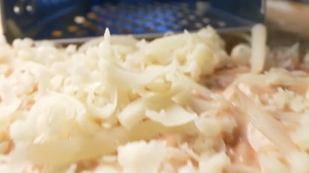 Πολύ κοντά. Τριμμένο τυρί σε σιδερένιο τρίφτη. διαδικασία μαγειρέματος — Αρχείο Βίντεο