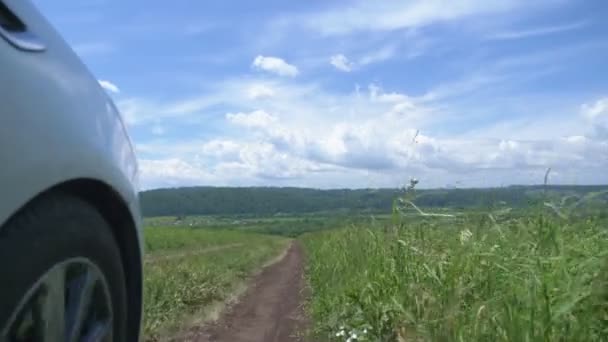 Closeup the wheel of a car moving across the field on the background of blue sky — Stock Video