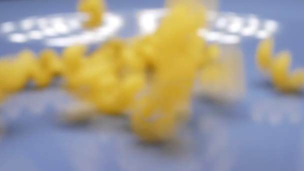 Сухі макаронні спіралі посипають синьою тарілкою. супер крупним планом — стокове відео