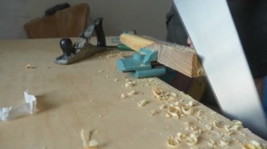 Kapat. Erkek elleri içeride testere ile tahta bir çubuğu kesiyor.