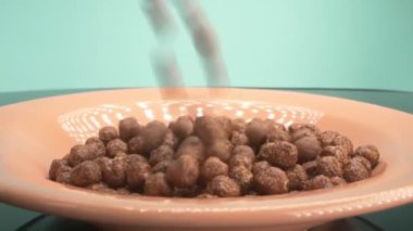 Kahvaltı gevrekleri çikolatalı mısır topları şeklinde tabağa serpiştiriliyor.