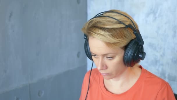 Жінка виробляє електронну музику в студії з ноутбуком і міді-клавіатурою — стокове відео