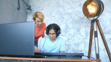 Stüdyoda birlikte çalan kadın ve çocuk midi klavye ve dizüstü bilgisayarla