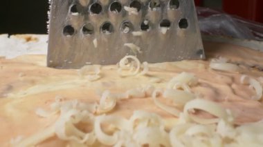 Süper yakın çekim. Demir rendesinde rendelenmiş peynir. yemek pişirme süreci