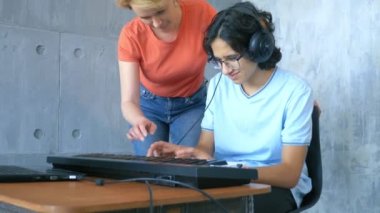 Stüdyoda birlikte çalan kadın ve çocuk midi klavye ve dizüstü bilgisayarla
