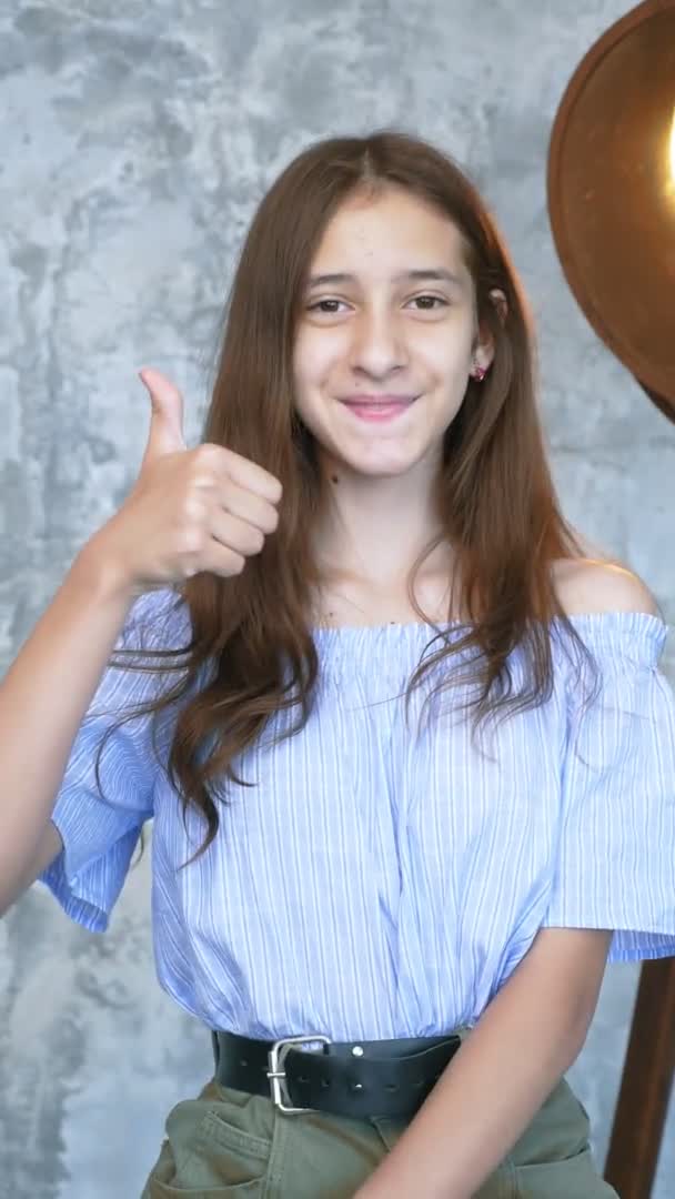 Pionowo, portret. dziewczyna w studio pokazując kciuki w górę gesty — Wideo stockowe