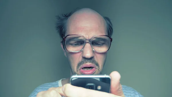 Plešatý muž s brýlemi stěží používá smartphone. Humor — Stock fotografie