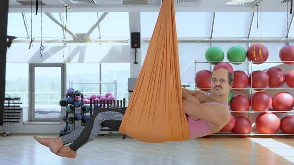 Un hombre seguro y calvo en ejercicios aéreos de yoga — Foto de Stock