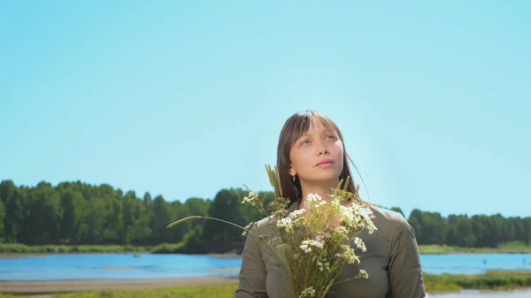 Porträt eines schönen Mädchens mit einem Strauß wilder Blumen an einem sonnigen Sommertag — Stockfoto