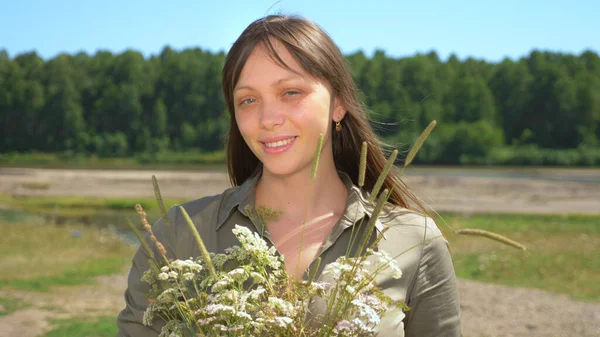 Porträt eines schönen Mädchens mit einem Strauß wilder Blumen an einem sonnigen Sommertag — Stockfoto