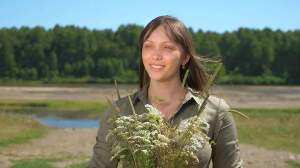 Porträt eines schönen Mädchens mit einem Strauß wilder Blumen an einem sonnigen Sommertag — Stockfoto