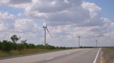 Mavi gökyüzüne karşı yol boyunca modern yel değirmenleri