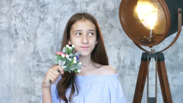 Портрет. мила дівчина-підліток з букетом квітів дивиться на камеру — стокове відео