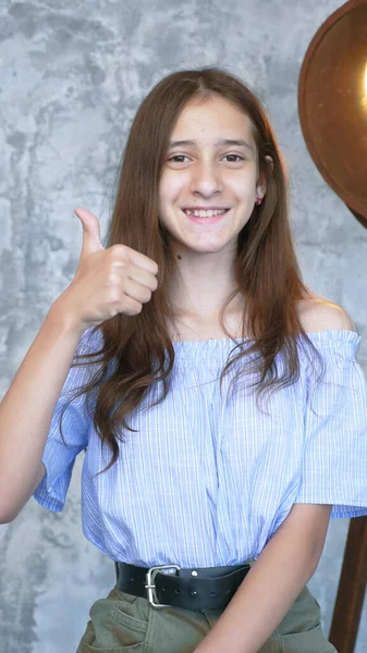 Verticaal. portret. meisje in de studio tonen duimen tot gebaren — Stockfoto