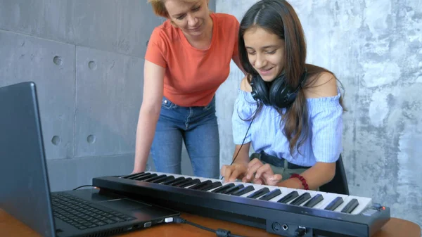 Mujer y chica jugando teclado midi y portátil juntos en el estudio — Foto de Stock