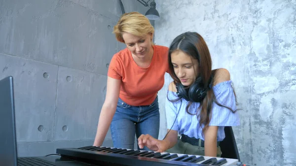 Mujer y chica jugando teclado midi y portátil juntos en el estudio — Foto de Stock