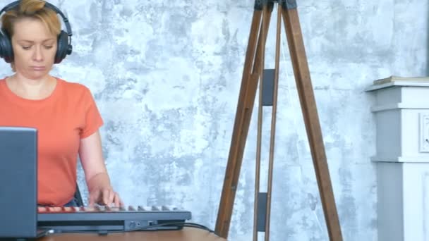 Vrouw produceert elektronische muziek in de studio met een laptop en midi toetsenbord — Stockvideo