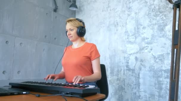 스튜디오에서 노트북과 미디 키보드로 전자 음악을 만드는 여성 — 비디오