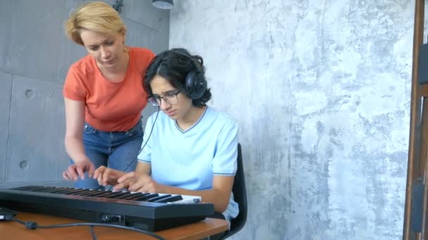 Kvinna och pojke spelar tillsammans i studio på midi tangentbord och laptop — Stockvideo