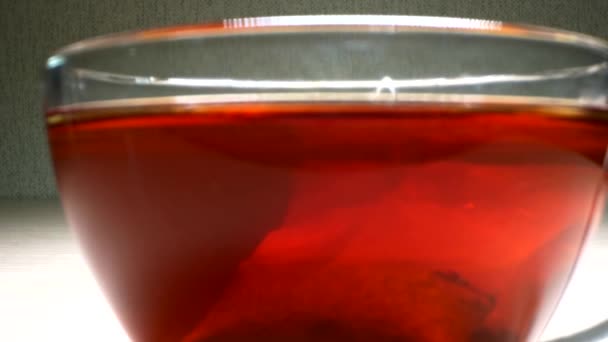 Súper cerca. detalles. elaboración de bolsas de té negro en una taza transparente — Vídeos de Stock