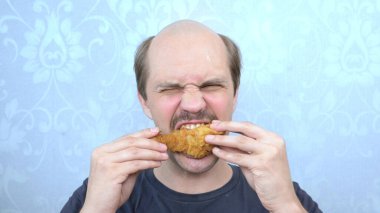 Bıyıklı kel bir adam tavuk budu yiyor. Yakın çekim..