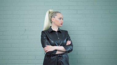 Deri gömlekli afro örgülü bir kadın. Arka plandaki tuğla duvar. Stüdyo çekimi