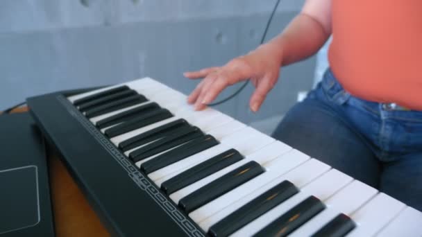 女性はラップトップとミディキーボードでスタジオで電子音楽を制作します — ストック動画